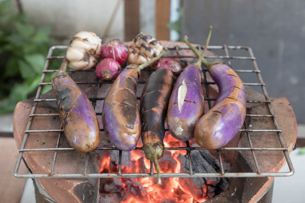 This photo shows aubergines cooking obver hot coals