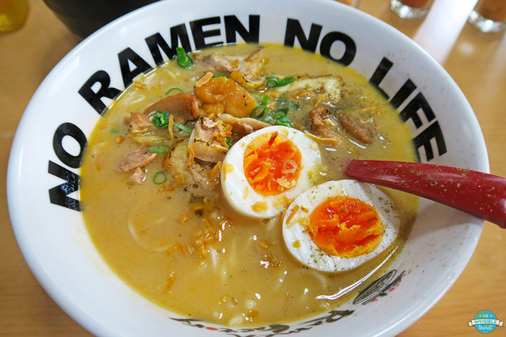 This photo shows a bowl of ramen topped with a halved hard-boiled egg