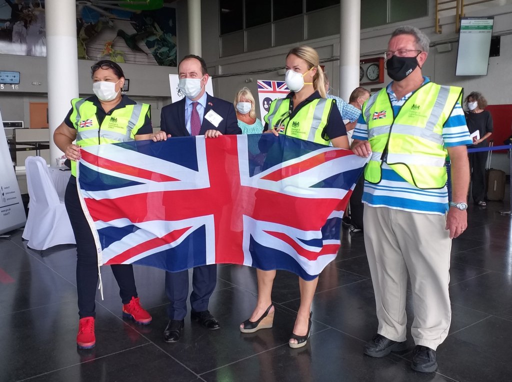 This photo shows the High Commission team wearing masks and hi-viz jackets and holding the Union Flag