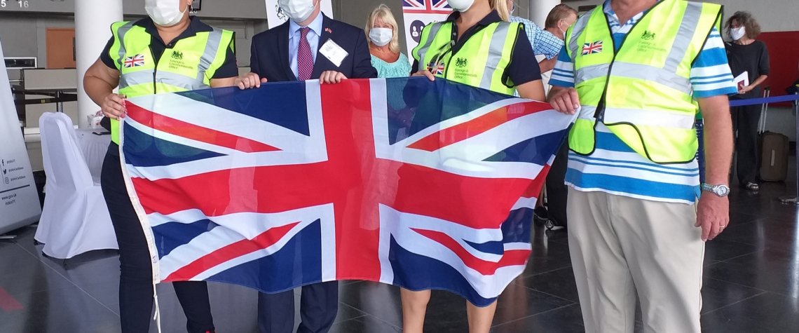 This photo shows the High Commission team wearing masks and hi-viz jackets and holding the Union Flag