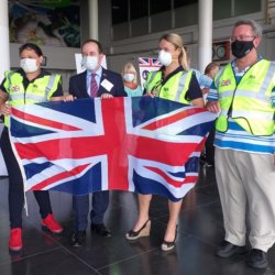 This photo shows the High Commission team wearing masks and hi-viz jackets and holding the Union Flag