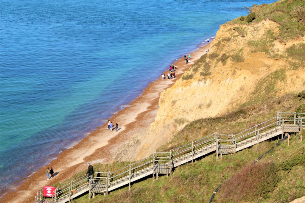 This photo shows a wooden stairway descending a cliff to reach a beach