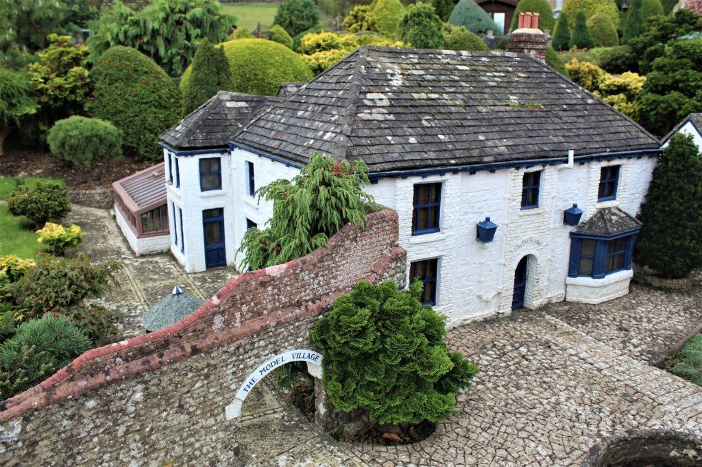 This photo shows a model of a whitewashed cottage with a tiled roof