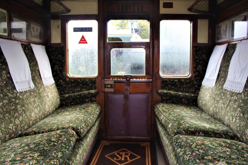 This photo shows a six-seater railway compartment with plush green upholstery