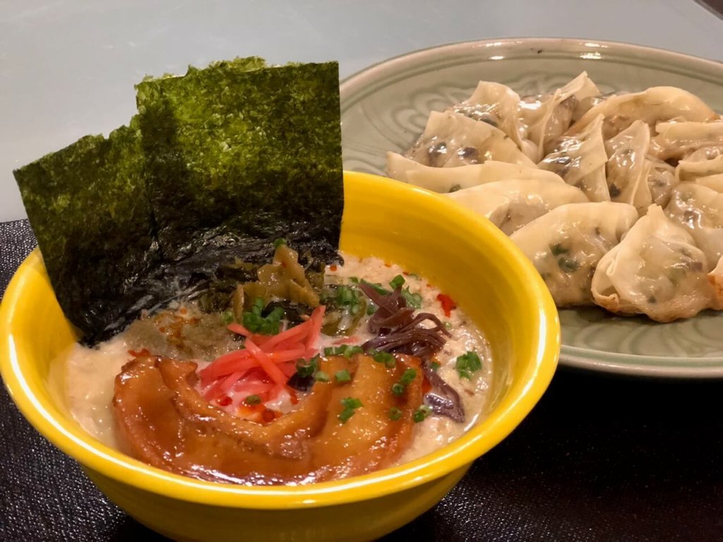 This picture shows a bowl of ramen and a plate of Japanese dumplings