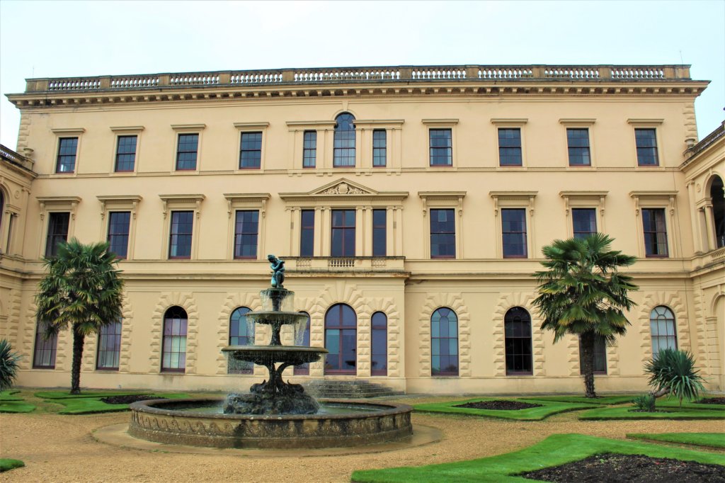 This photo shows the back of the house with its sandstone facade and an elaborate fountain inthe foreground
