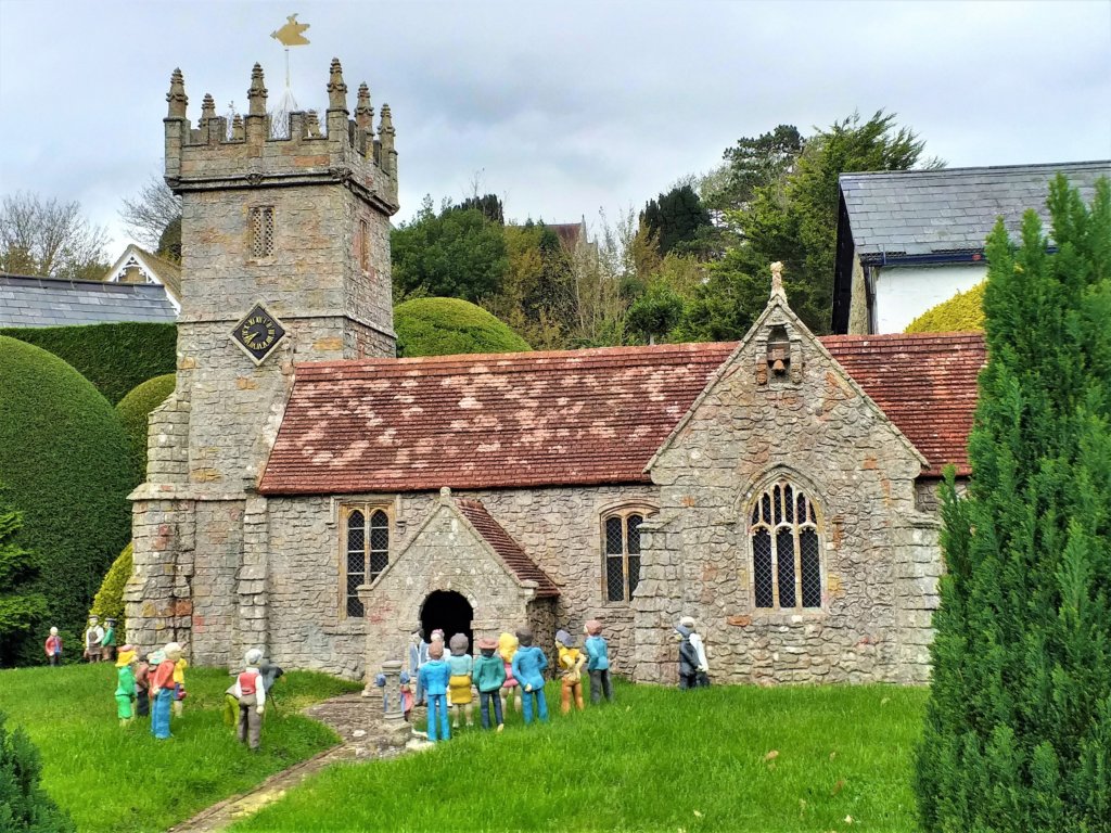 This photo shows a model of the village church with people gathered on the lawn outside