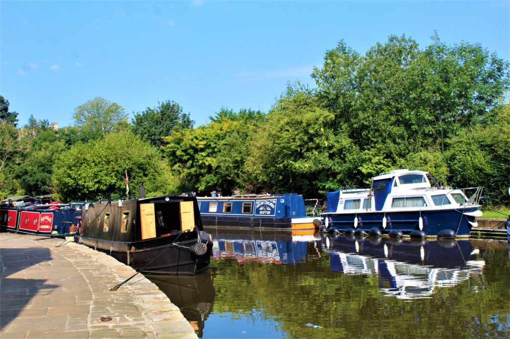 This photo shows colourful barges reflected in the water of the canal