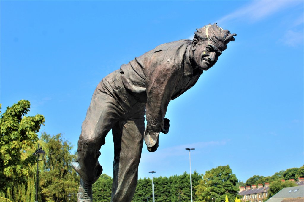 This photo shows the bronze statue of Freddie Trueman bowling in a cricket match