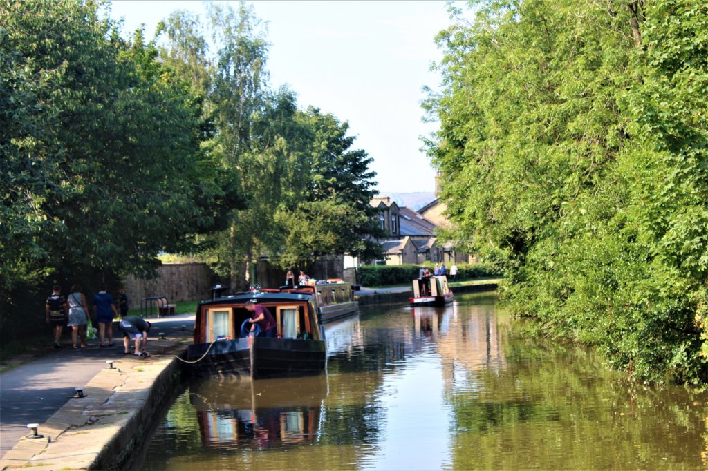 This photo shows boats on the canal and people walking along the towpath