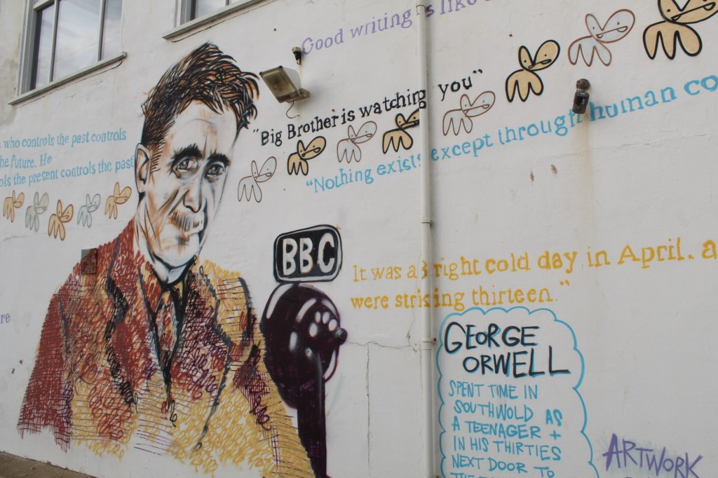 This photo shows a wall painted with a portrait of George Orwell surrounded by quotes from his writings
