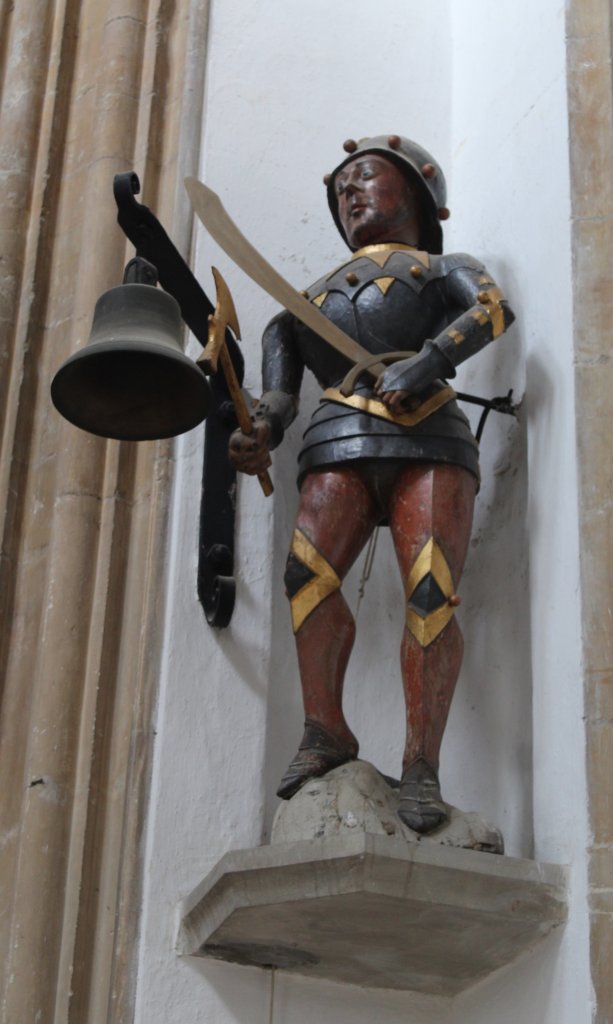 This photo shows a model of Southwold Jack holding the bell that is rung at the start of every service held at the church of St Edmund