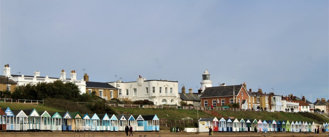 This photo shows an expanse of sandy beach with beach huts in the distance