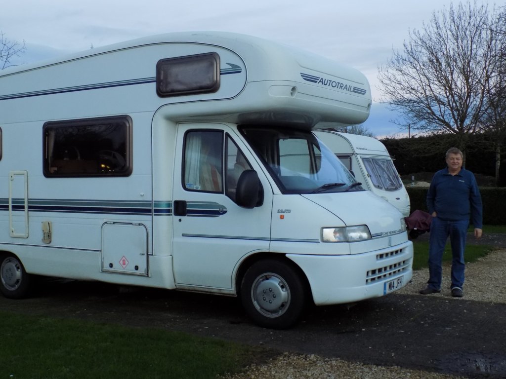 This photo shows our white motorhome parked up in the dusk of a summer's evening