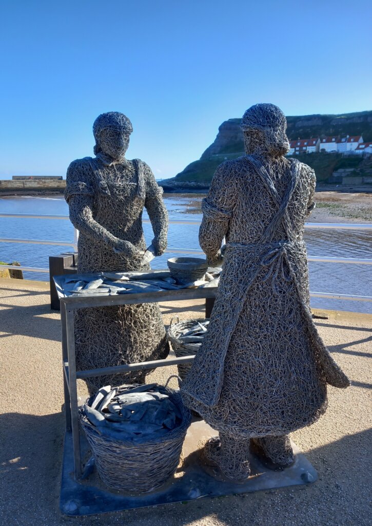 This image shows a sculpture of two herring girls gutting fish