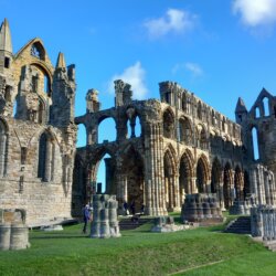 This photo shows a wide view of Whitby Abbey ruins set against an azure blue sky