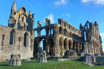 This photo shows a wide view of Whitby Abbey ruins set against an azure blue sky