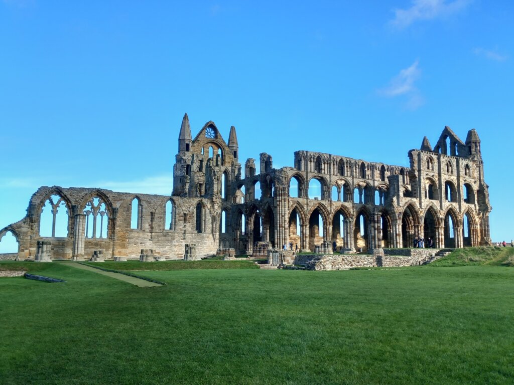 This photo shows the ruins of Whitby Abbey on a beautiful sunny day