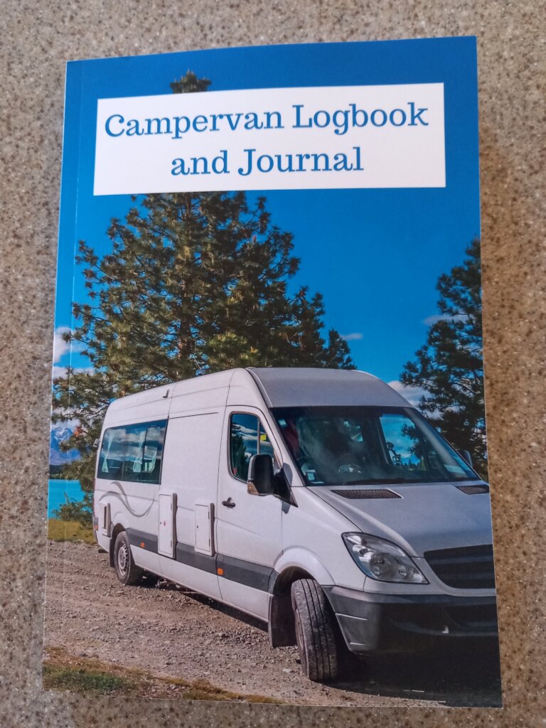 This photo shows the front cover of my campervan journal.  It shows a grey campervan parked in front of trees.