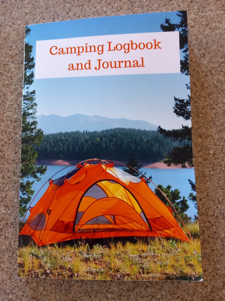 This photo shows the front cover of my camping journal.  It shows an orange tent pitched in front of a lake