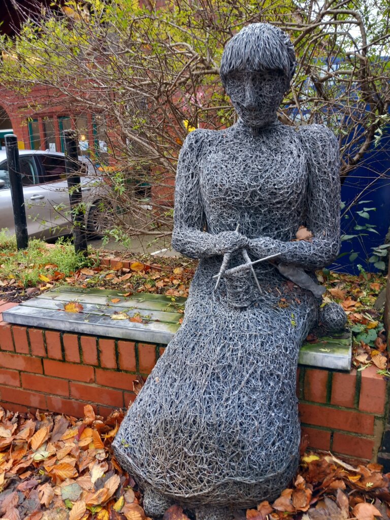 This photo is of a sculpture in Whitby's Walk with Heritage Trail.  It shows a lady sitting on a bench knitting a sweater.