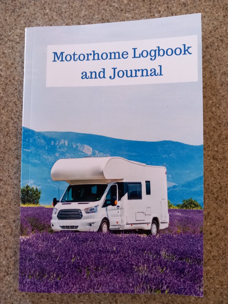 This photo shows the front cover of my motorhome logbook.  It is a white motorhome parked in a field of vibrant lavender