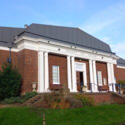 This photo shows the front of the building that houses Whitby Museum and Art Gallery. It is red-brick built with white columns at the front.