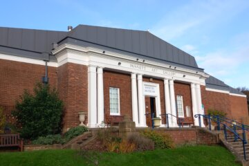 This photo shows the front of the building that houses Whitby Museum and Art Gallery. It is red-brick built with white columns at the front.