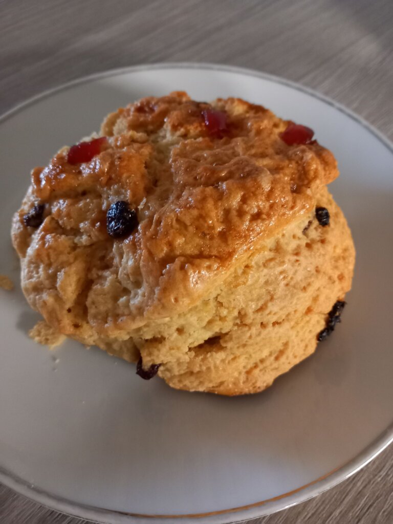 This photo shows a large golden brown scone with currants and sultana clearly visible