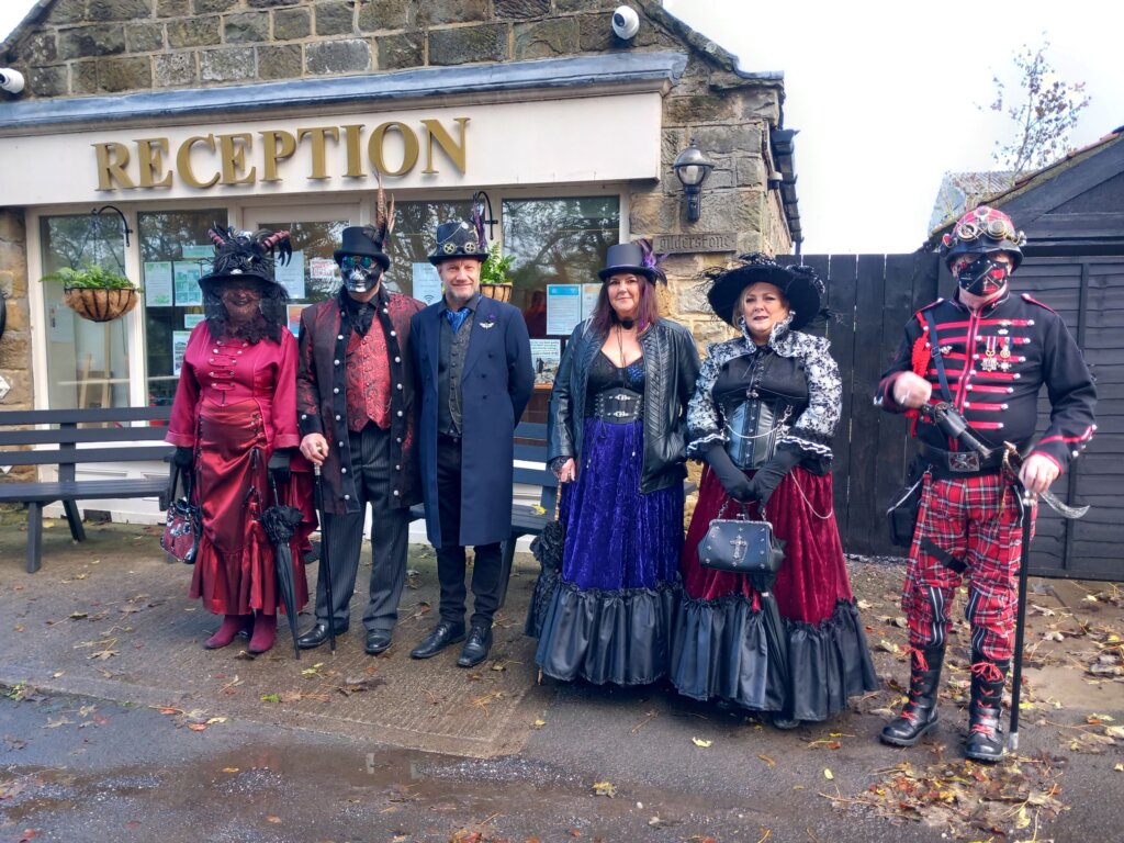 This photo shows a group of three men and three women dressed in Goth costumes