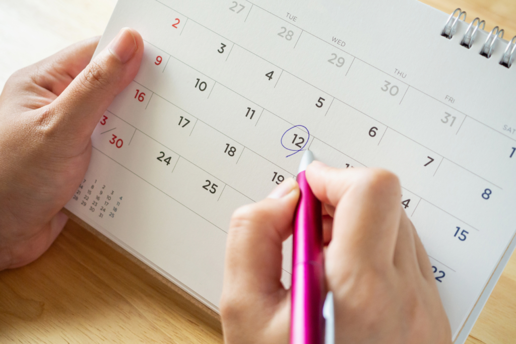 This photo shows someone planning when to start their trip.  They are holding a calendar and circling a date.