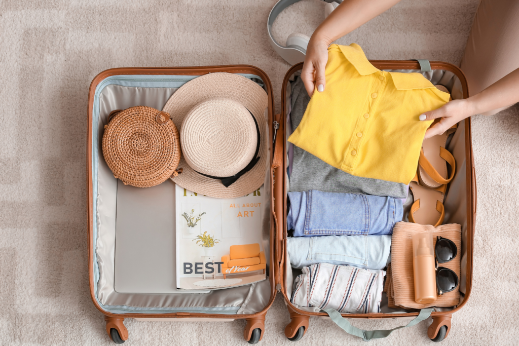 This photo shows someone packing a small brown suitcase