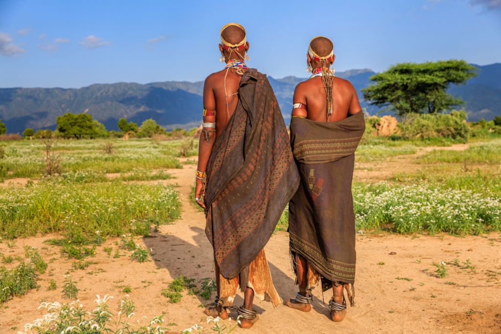This photo shows 2 men in traditional dress with their backs to camera looking out over the Ethiopian countryside